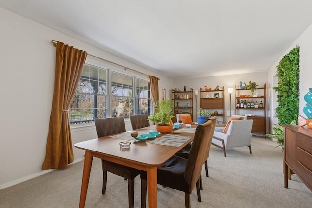 dining space with light carpet and baseboards