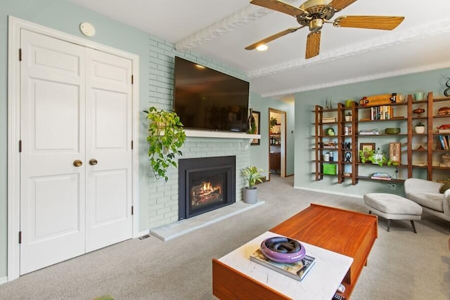 carpeted living room with beam ceiling, a brick fireplace, and a ceiling fan