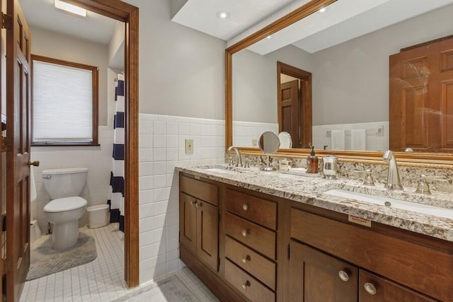 full bath with a sink, toilet, tile walls, and tile patterned floors