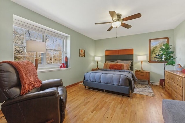 bedroom with light wood finished floors, a ceiling fan, and baseboards