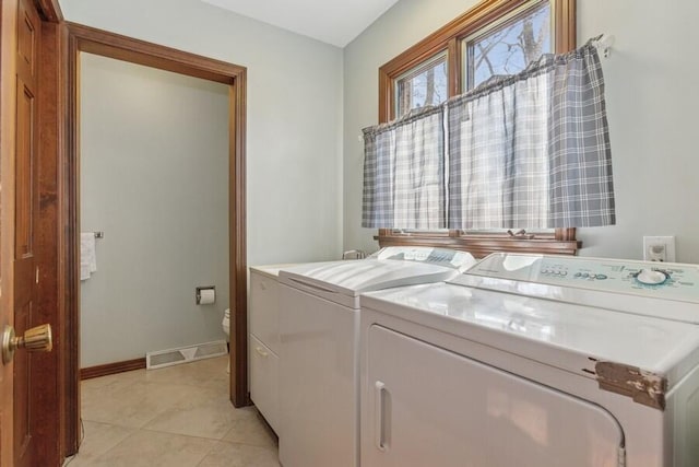 washroom featuring baseboards, visible vents, laundry area, light tile patterned flooring, and washer and dryer