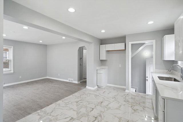 kitchen with recessed lighting, white cabinets, and a sink