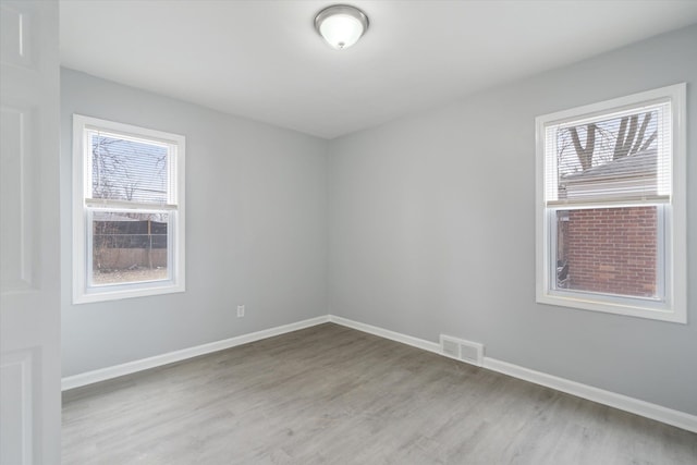 empty room featuring visible vents, baseboards, and wood finished floors