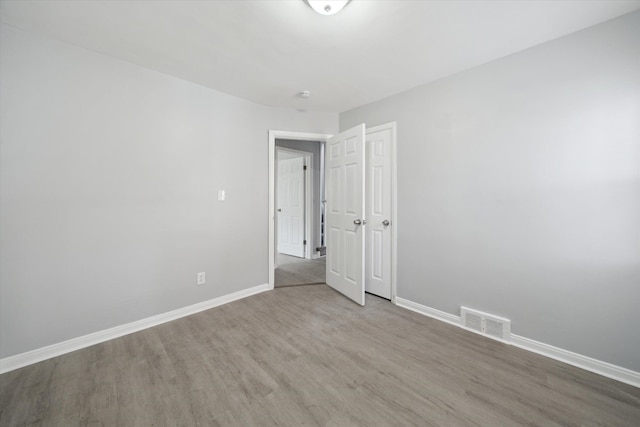 empty room with wood finished floors, baseboards, and visible vents