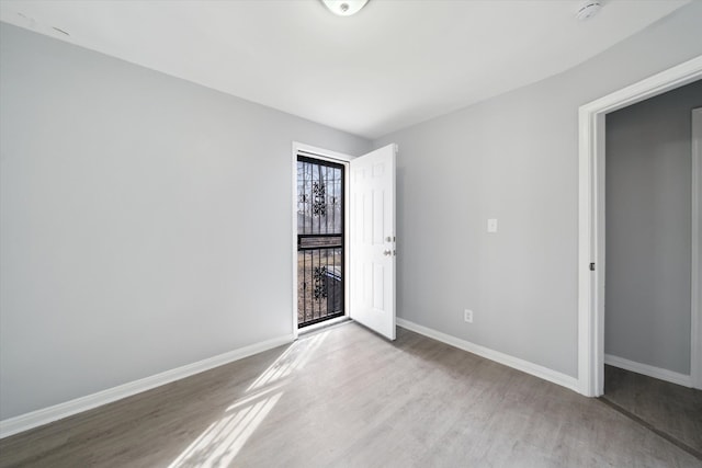 spare room with baseboards and wood finished floors