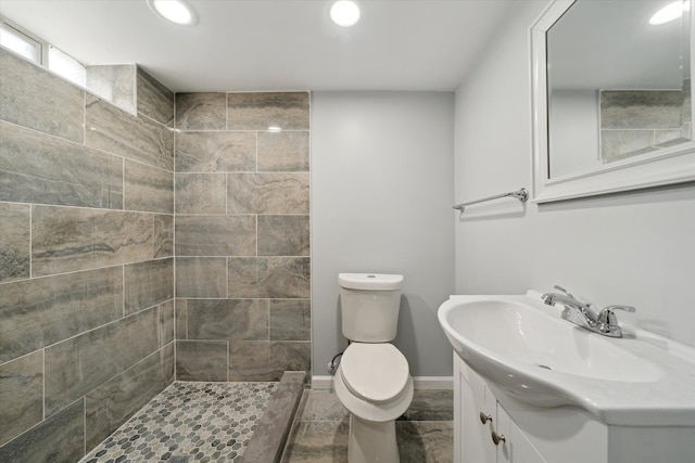 bathroom with vanity, baseboards, recessed lighting, a tile shower, and toilet