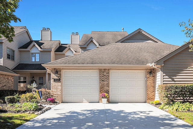 view of front of house with an attached garage, brick siding, driveway, and roof with shingles