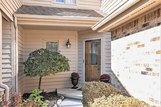 entrance to property featuring roof with shingles