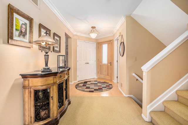 entryway with stairs, crown molding, wood finished floors, and baseboards