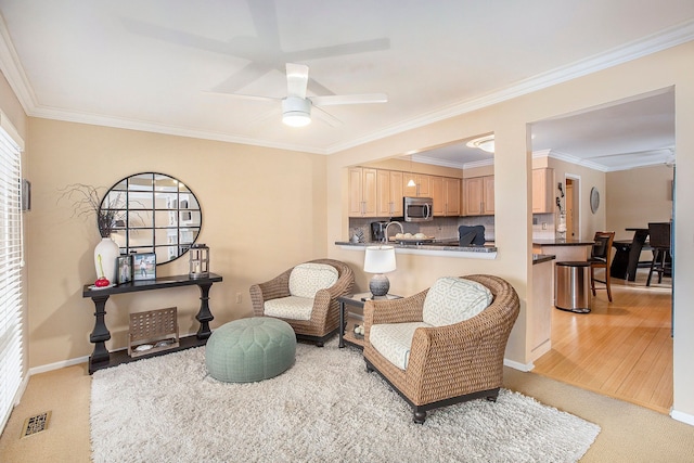 sitting room featuring baseboards, visible vents, ornamental molding, ceiling fan, and light colored carpet