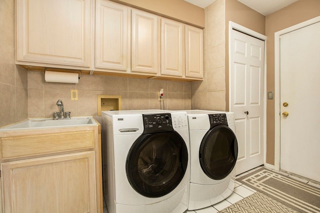 laundry area featuring a sink, tile walls, cabinet space, and washer and clothes dryer