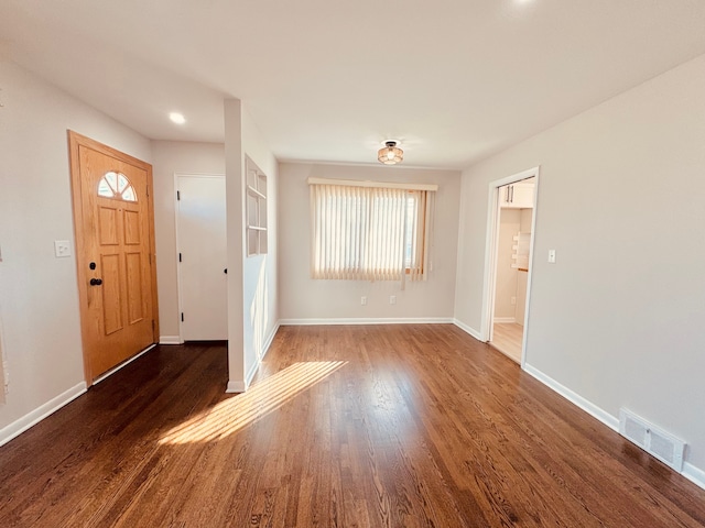 foyer entrance featuring visible vents, baseboards, and wood finished floors