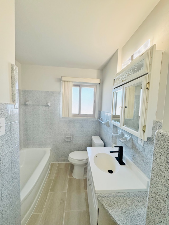 full bath with vanity, washtub / shower combination, wainscoting, tile walls, and toilet