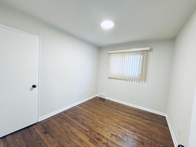 spare room with visible vents, baseboards, and dark wood-style floors