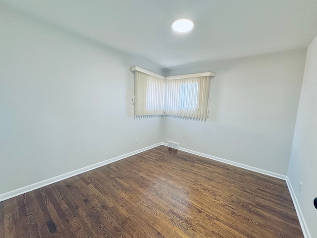 unfurnished room with visible vents, dark wood-type flooring, and baseboards