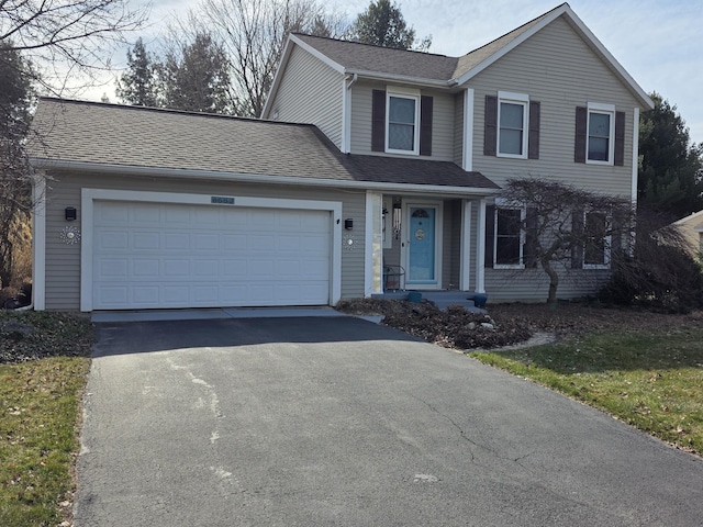 traditional home with aphalt driveway, an attached garage, and a shingled roof