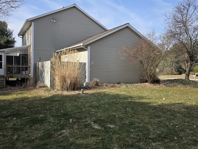 view of home's exterior featuring a lawn, fence, and a sunroom