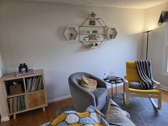 sitting room with baseboards and wood finished floors