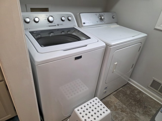 washroom featuring washing machine and clothes dryer, laundry area, baseboards, and visible vents