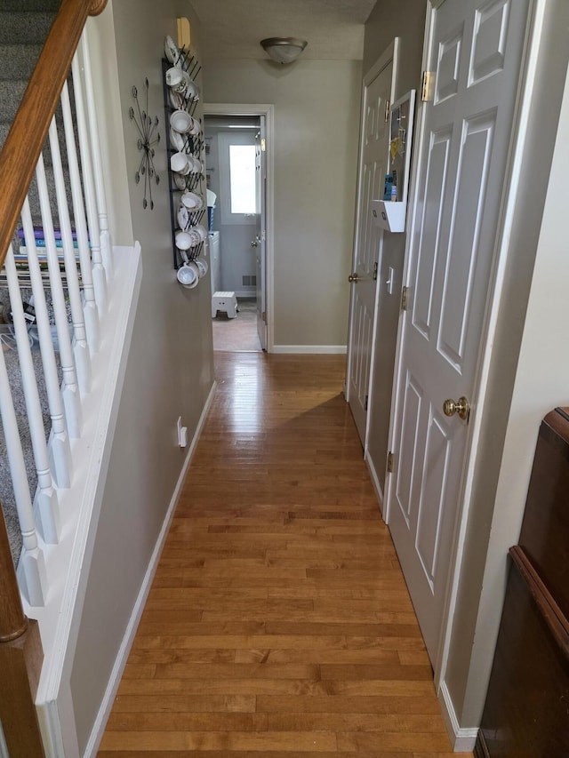 hall with stairway, baseboards, and light wood-style flooring