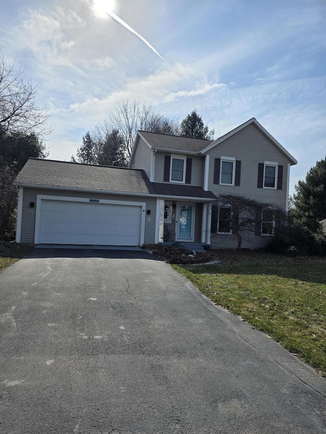 traditional home with aphalt driveway, a front lawn, a garage, and roof with shingles