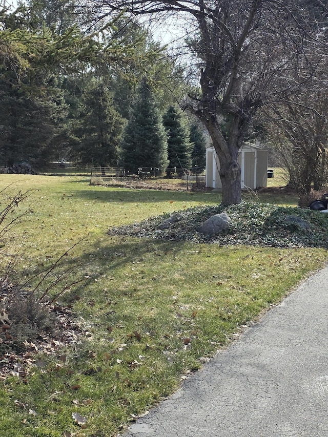 view of yard featuring an outbuilding, a storage shed, and fence