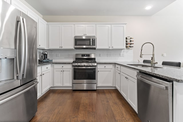 kitchen featuring a sink, dark wood finished floors, appliances with stainless steel finishes, white cabinets, and decorative backsplash