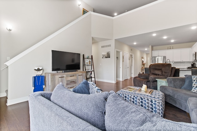 living area with visible vents, baseboards, recessed lighting, a high ceiling, and dark wood-style floors