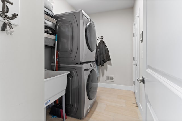 laundry area featuring laundry area, baseboards, visible vents, and stacked washer and dryer