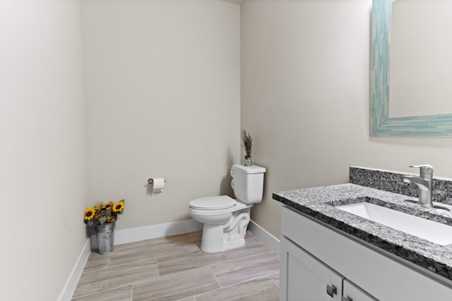 bathroom with baseboards, toilet, and vanity