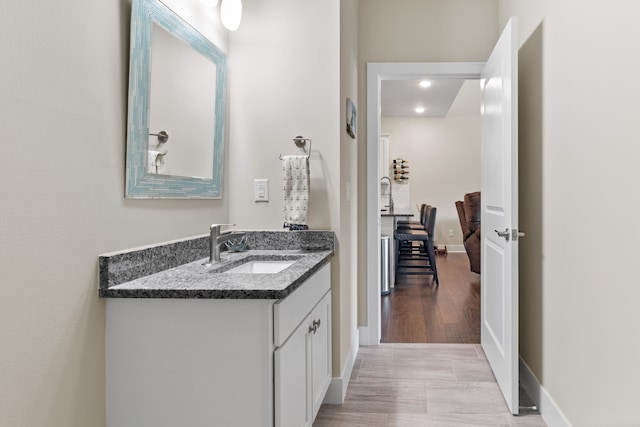 bathroom featuring baseboards, wood finished floors, and vanity