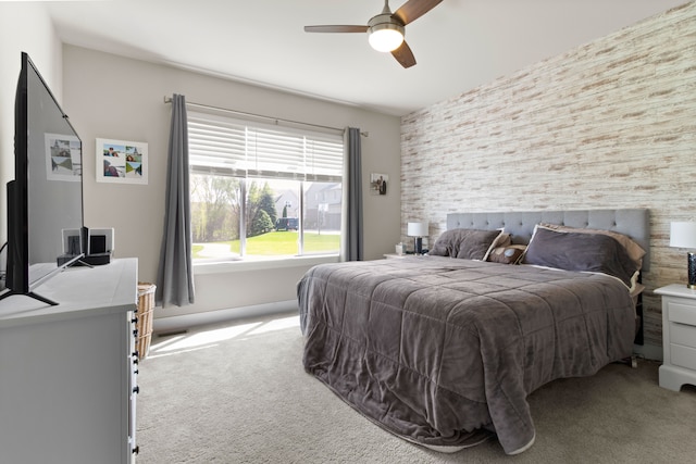 bedroom featuring light colored carpet, an accent wall, and a ceiling fan