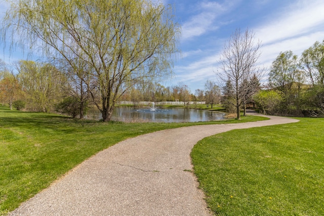 view of property's community with a lawn and a water view