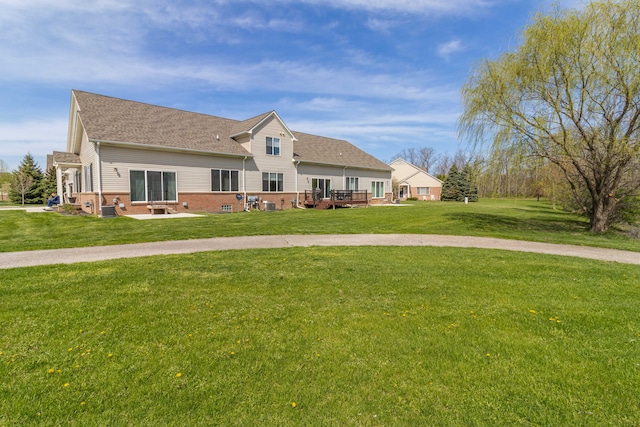 view of front of property featuring brick siding, central AC, a front yard, and a shingled roof