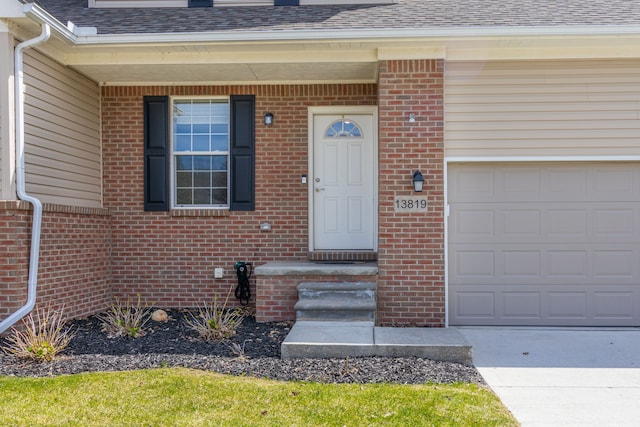 entrance to property with an attached garage, brick siding, roof with shingles, and driveway