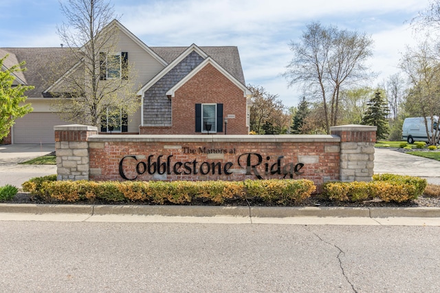 community / neighborhood sign with concrete driveway and a garage