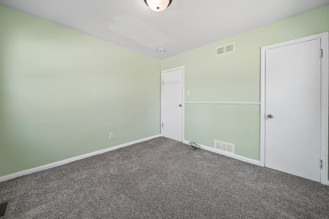 unfurnished bedroom with baseboards, visible vents, and dark colored carpet