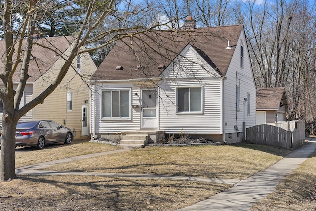 view of front of home with entry steps, a front lawn, a chimney, and a shingled roof