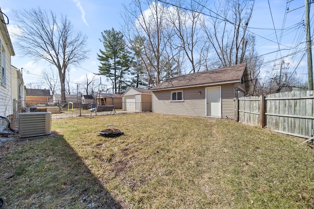 view of yard featuring an outbuilding, fence, a garage, and central AC