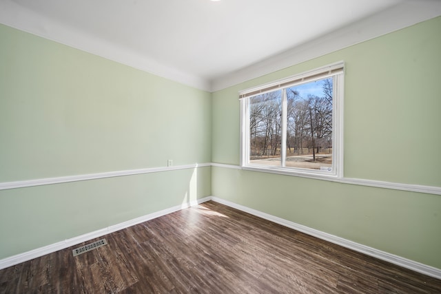 empty room with visible vents, baseboards, and wood finished floors