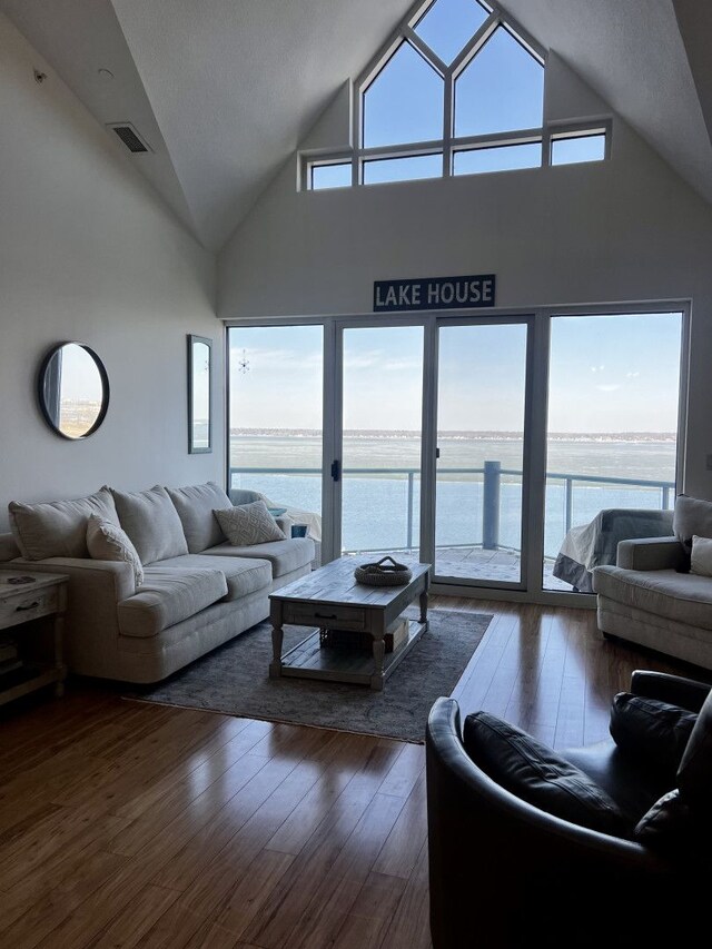 living room featuring a wealth of natural light, visible vents, a water view, and dark wood-style flooring