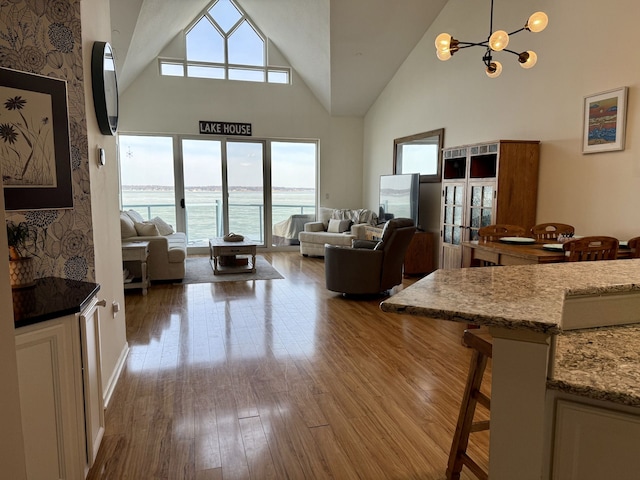 living room with french doors, a notable chandelier, wood finished floors, and high vaulted ceiling