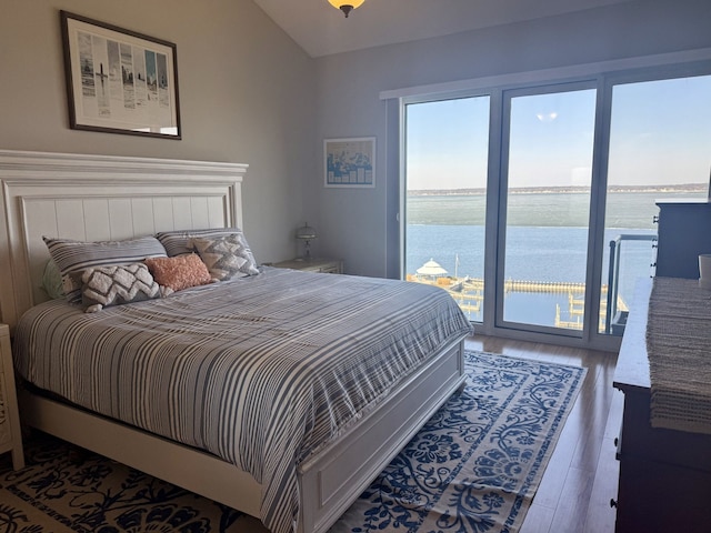 bedroom with access to exterior, wood finished floors, lofted ceiling, and a water view