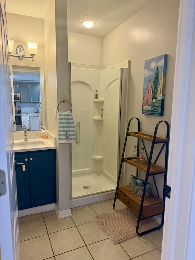 bathroom with vanity, tile patterned floors, a stall shower, and a textured ceiling