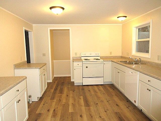 kitchen featuring a sink, light countertops, white appliances, white cabinetry, and dark wood-style flooring