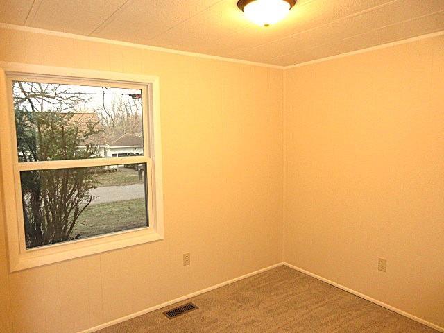 spare room featuring crown molding, carpet flooring, baseboards, and visible vents