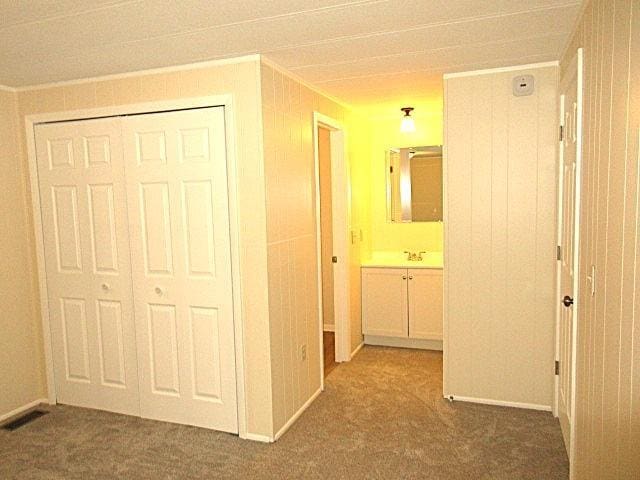 hall with carpet flooring, visible vents, and a sink