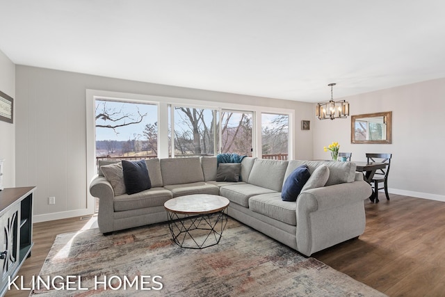 living area with dark wood finished floors, baseboards, and a chandelier