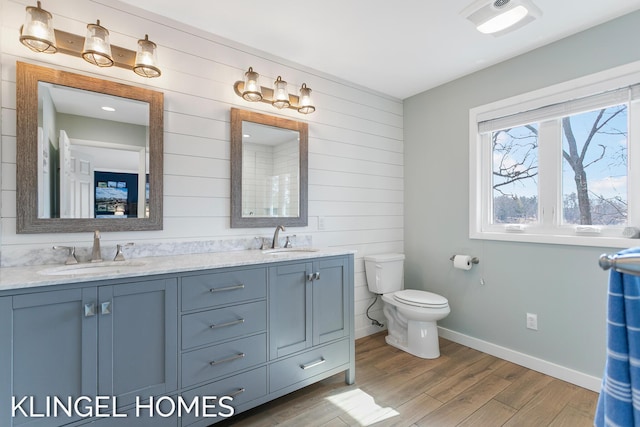 bathroom featuring a sink, toilet, wood finished floors, and double vanity