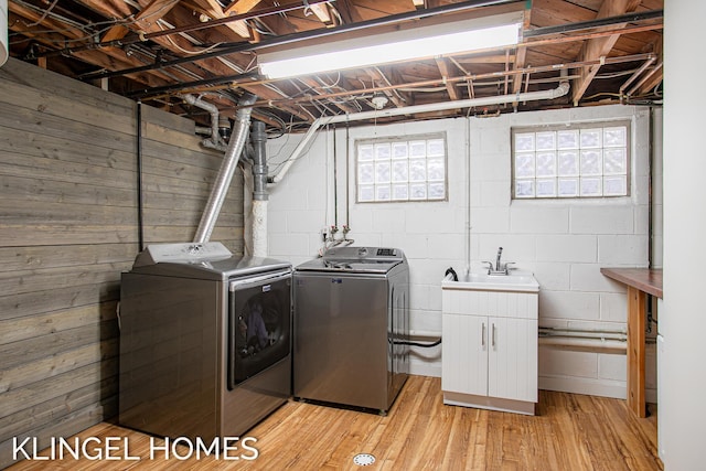 washroom featuring cabinet space, light wood-style flooring, washing machine and dryer, and a sink